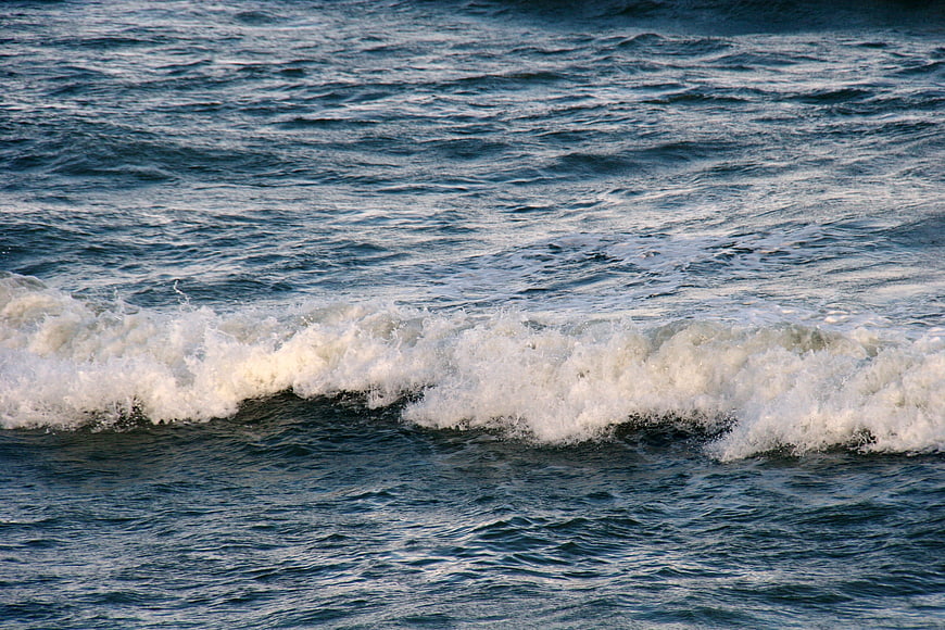 Crashing ocean wave with white foam on blue water
