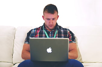 Man working on laptop while sitting on white sofa