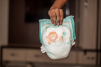 Hand holding a baby diaper with lion design in a bathroom