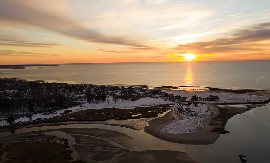 Aerial View of Snowy Coastal Village at Golden Sunset