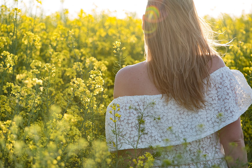 Woman in White Lace Dress Standing in Yellow Flower Field