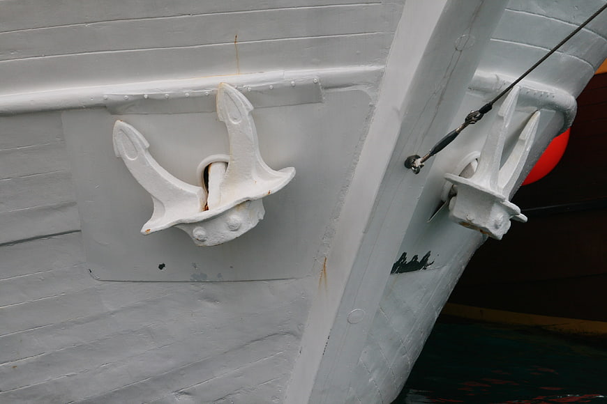 Close-up of white boat hull with anchor and cleat
