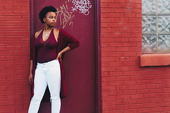 Confident Black Woman in Maroon Outfit Against Red Brick Wall