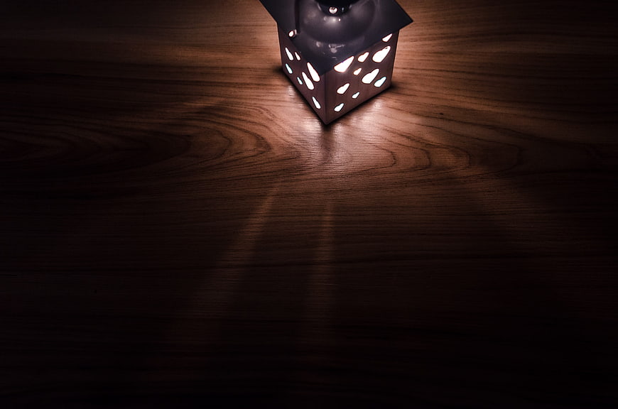 Vintage metal lantern glowing on dark wooden table background