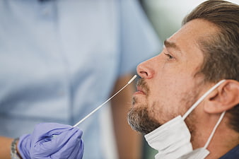 Close-up of man receiving nasal swab test by medical professional