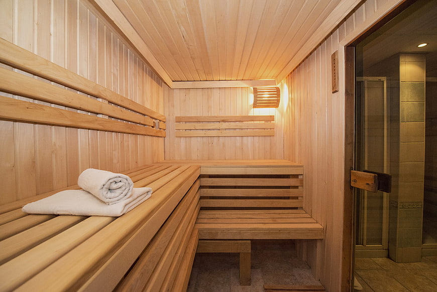 Cozy wooden sauna interior with white towels and glass door