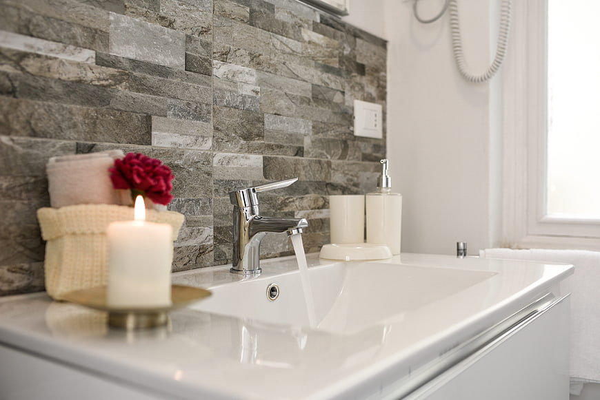 Modern Bathroom Sink With Candle, Towels, And Stone Wall