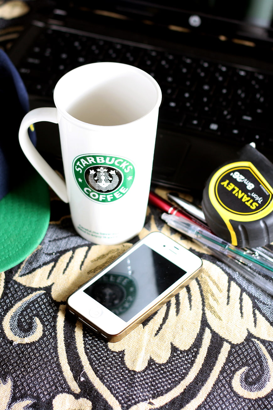 Starbucks mug, smartphone, and tools on patterned fabric