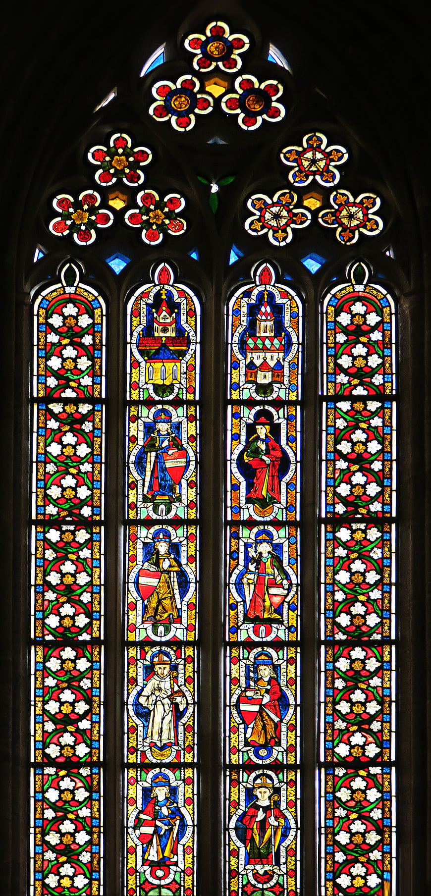 Gothic stained glass window with saints and floral patterns