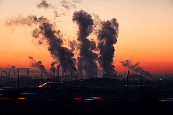 Industrial Factory Smoke Plumes Against Vibrant Orange Sunset Sky