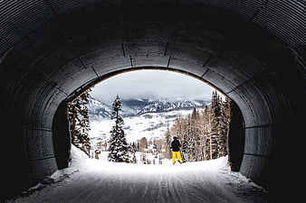 Skier exiting tunnel into snowy mountain landscape