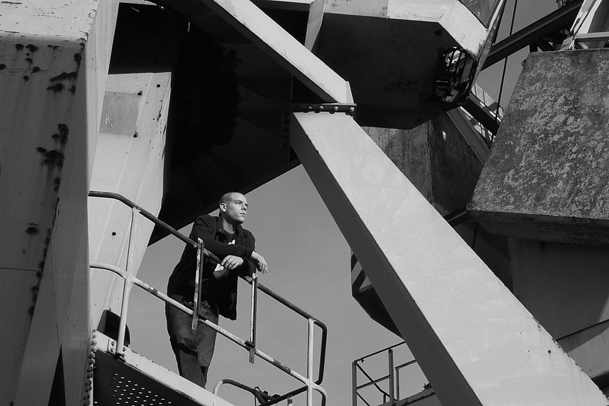 Man leaning on railing in industrial harbor crane structure
