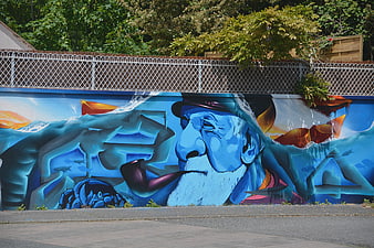 Blue graffiti mural of old man with pipe on wall