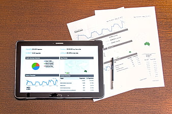 Tablet and printed analytics reports on wooden desk