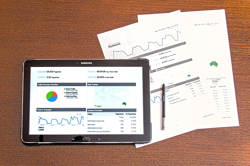 Tablet and printed analytics reports on wooden desk