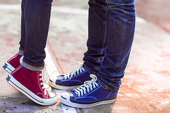 Couple's feet in red and blue sneakers on pavement