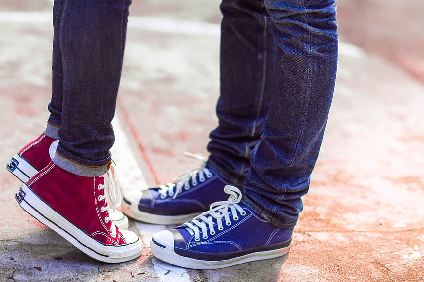 Couple's feet in red and blue sneakers on pavement