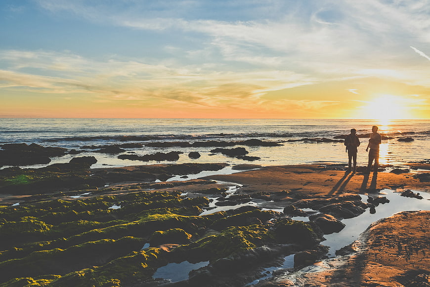 Couple Silhouette Watching Sunset on Rocky Beach
