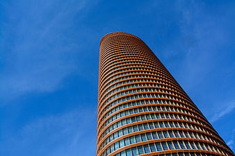Low angle view of modern cylindrical skyscraper against blue sky