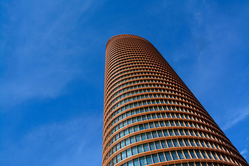 Low angle view of modern cylindrical skyscraper against blue sky