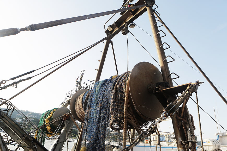 Fishing boat winch with blue net and ropes in harbor