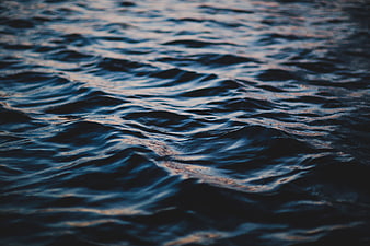 Close-up of dark blue ocean waves with subtle golden light reflections