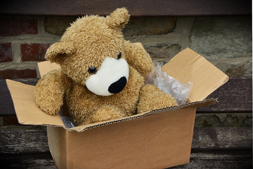 Teddy Bear In Cardboard Box On Wooden Bench