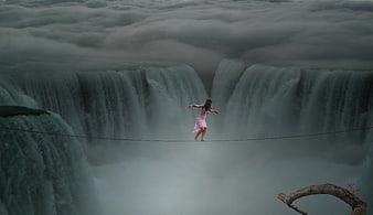 Woman tightrope walking over massive waterfall