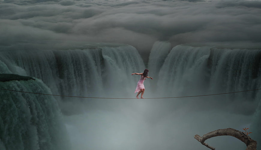 Woman tightrope walking over massive waterfall