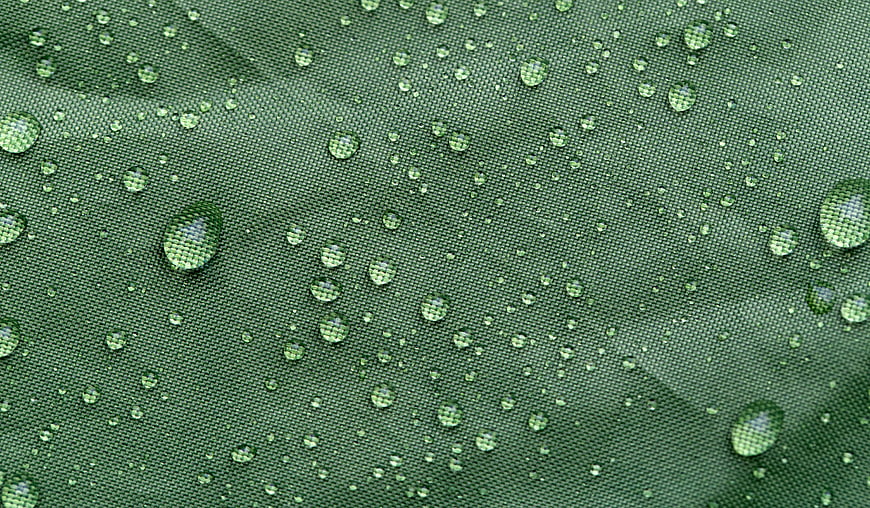 Macro shot of water droplets on green waterproof fabric texture