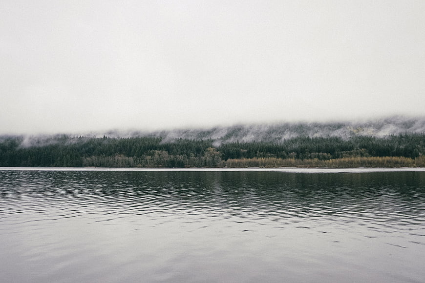 Serene Lake Landscape with Foggy Forest and Mountains