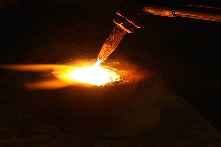 Industrial metal smelting with intense torch flame and sparks