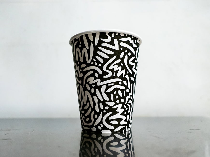 Black and White Patterned Paper Cup on Metal Surface