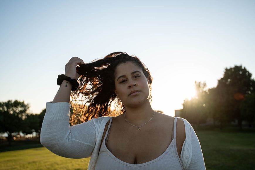Confident Woman with Curly Hair in Park at Sunset