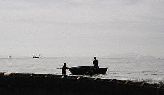 Silhouetted fishermen in a boat on calm sea