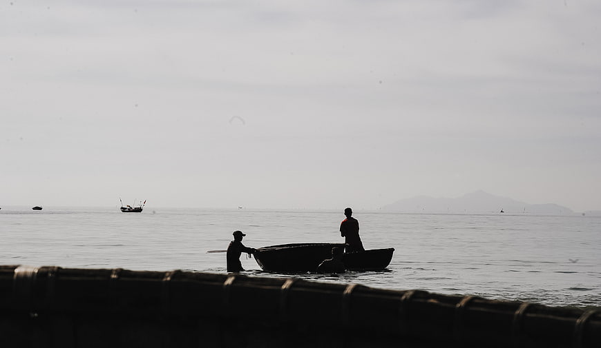 Silhouetted fishermen in a boat on calm sea