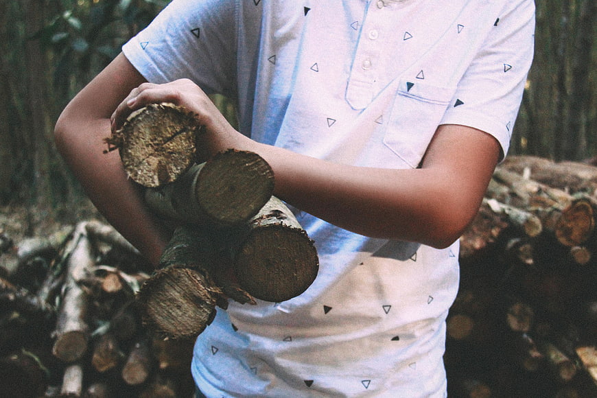 Man Carrying Firewood Logs in Forest