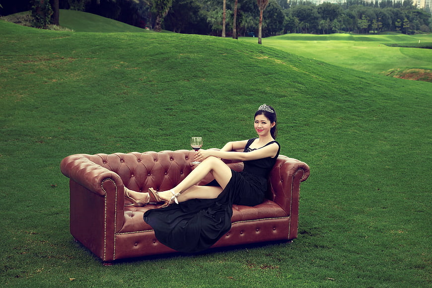 Elegant Woman in Black Dress on Leather Sofa in Park