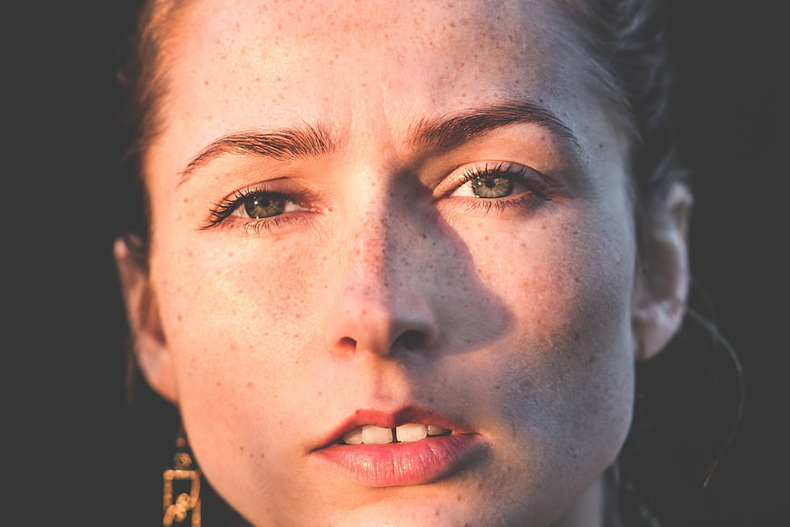Close-up portrait of a young woman with freckles and natural skin texture