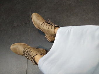 Top-down view of tan leather boots with white pants