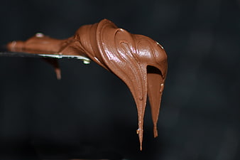 Close-up of thick chocolate spread dripping from a knife
