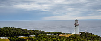 White Lighthouse on Green Coastal Cliff Overlooking Ocean