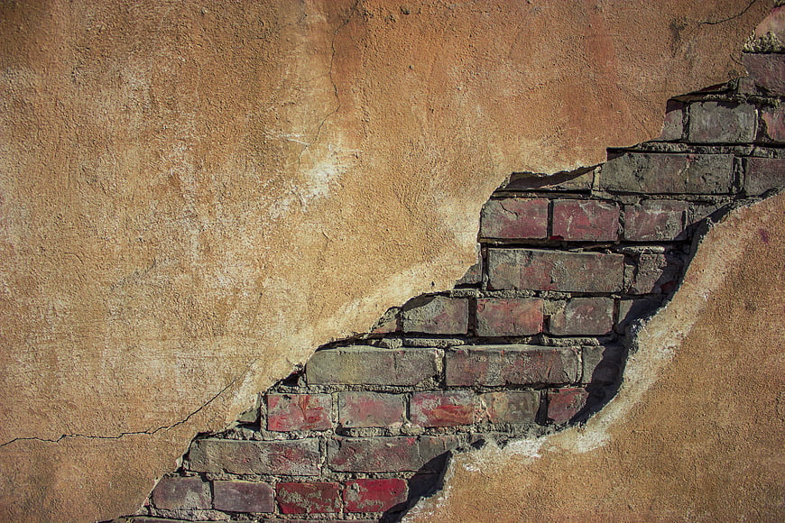 Textured plaster wall with exposed red brick layer