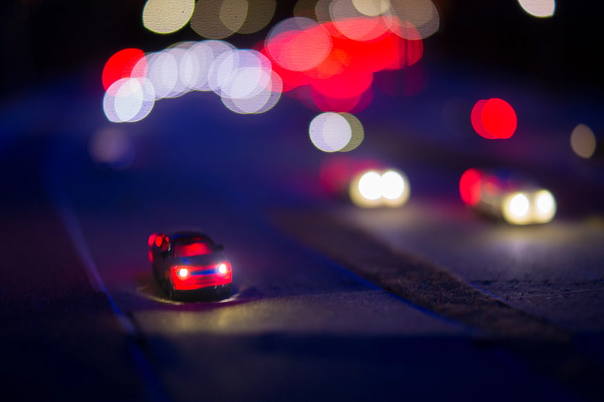 Toy car on road with bokeh lights at night