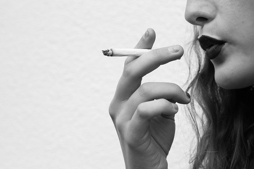 Close-up of woman smoking cigarette in black and white