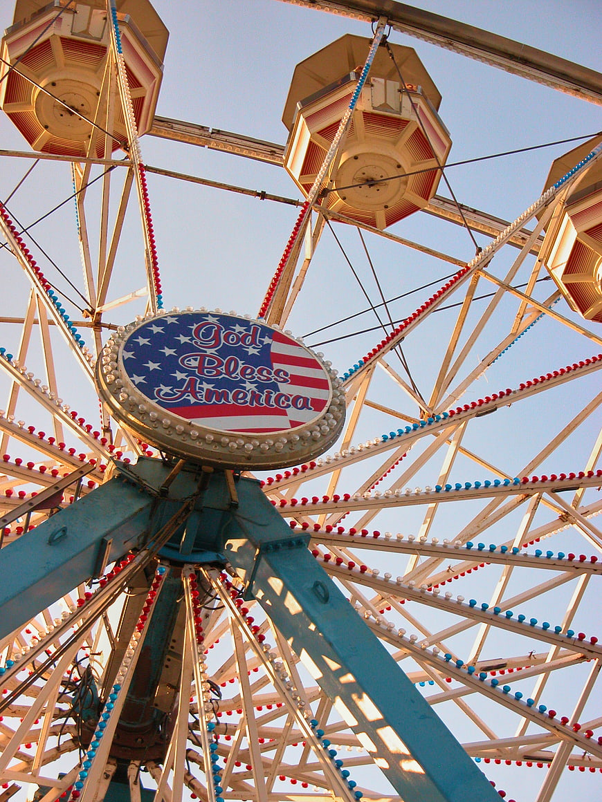 Low angle view of vintage Ferris wheel with patriotic sign