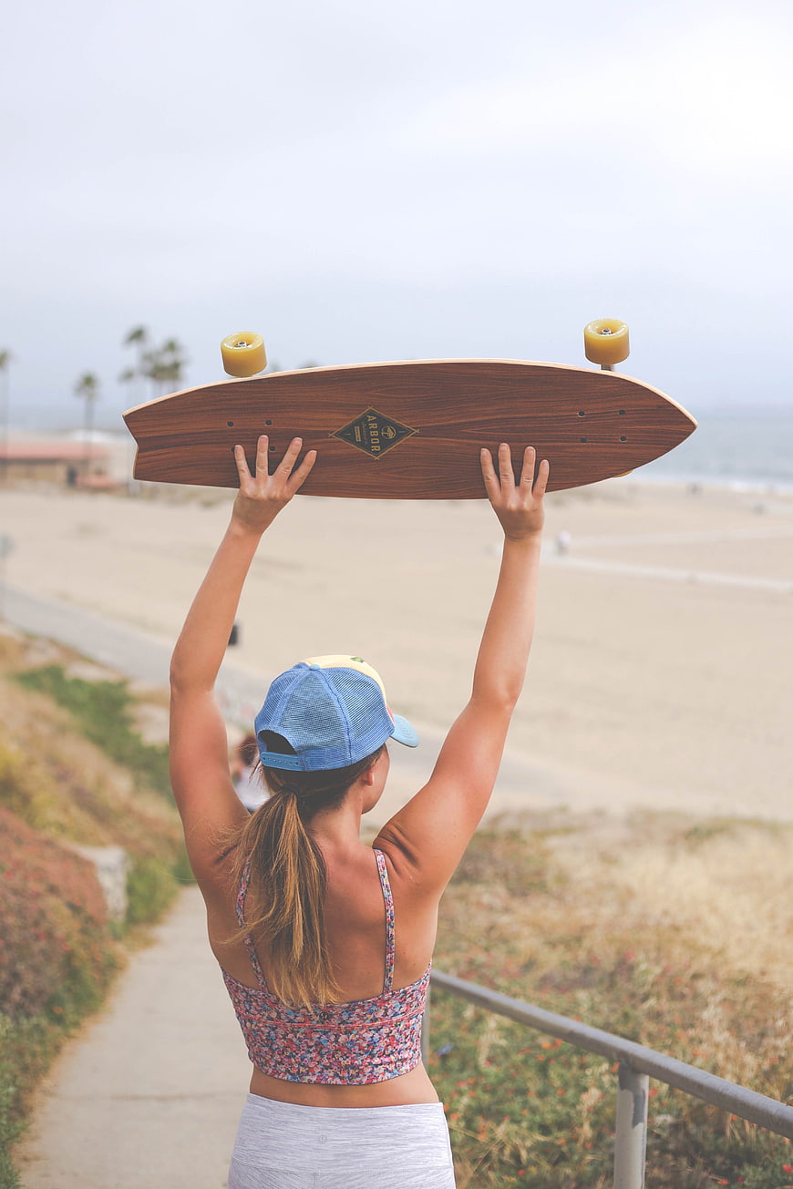 Woman holding longboard overlooking beach path