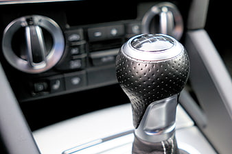 Close-up of a modern car gear shift knob with perforated leather and chrome details