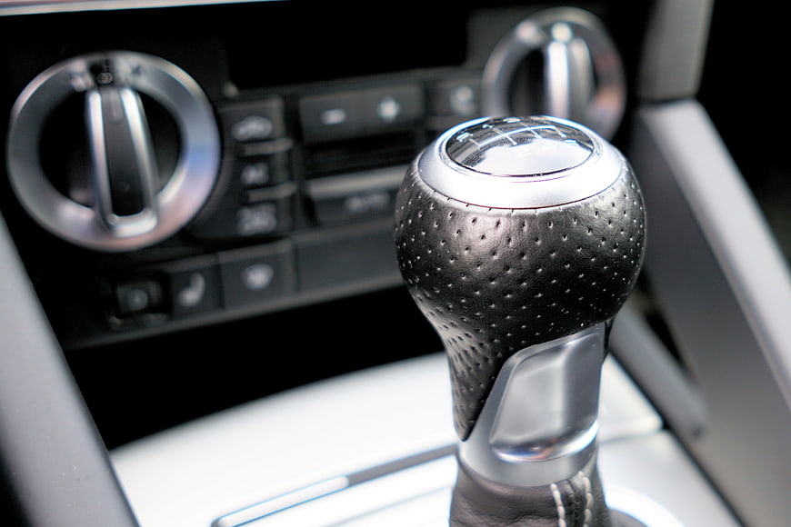 Close-up of a modern car gear shift knob with perforated leather and chrome details