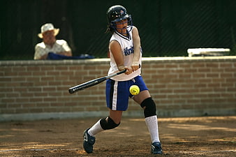 Female softball player hitting ball during game